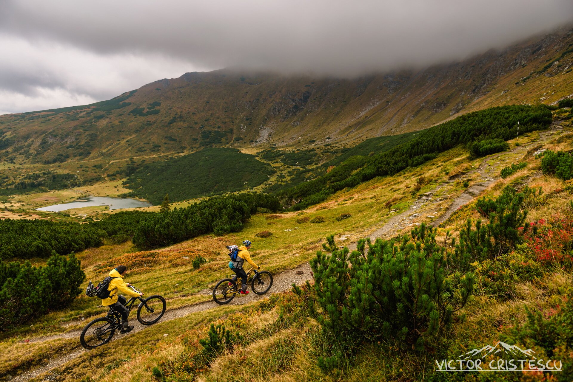 Two riders on an autumn alpine trail under low cloud in the Carpathians