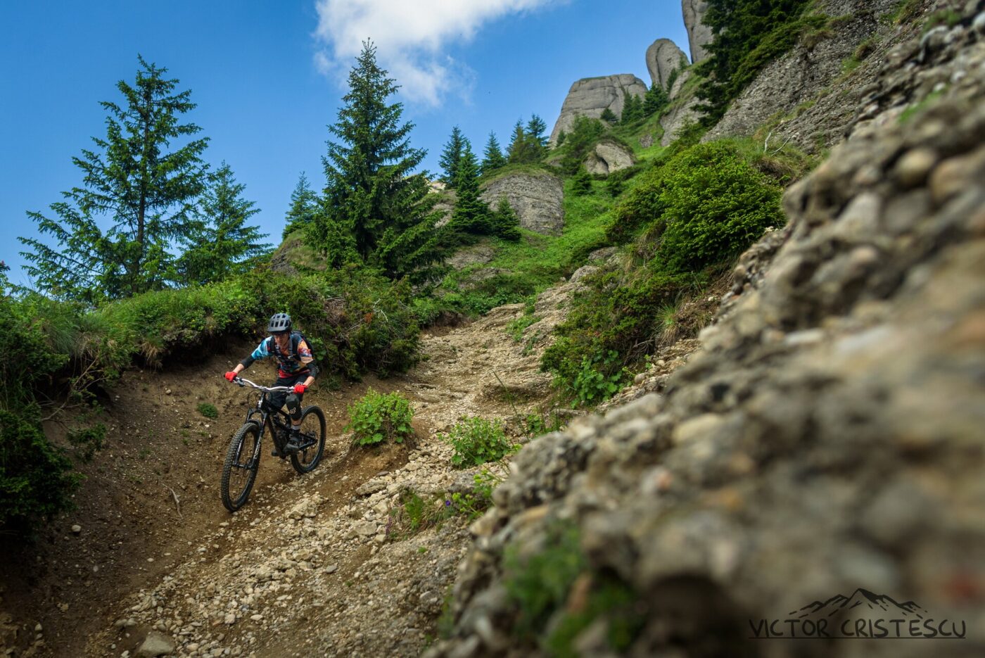 Mountain biker descending rocky singletrack beneath the Ciucaș towers, Romanian Carpathians