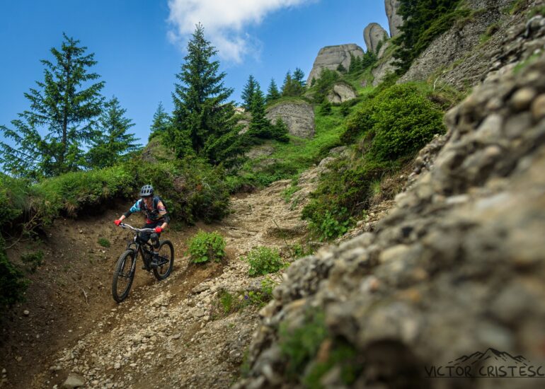 Mountain biker descending rocky singletrack beneath the Ciucaș towers, Romanian Carpathians