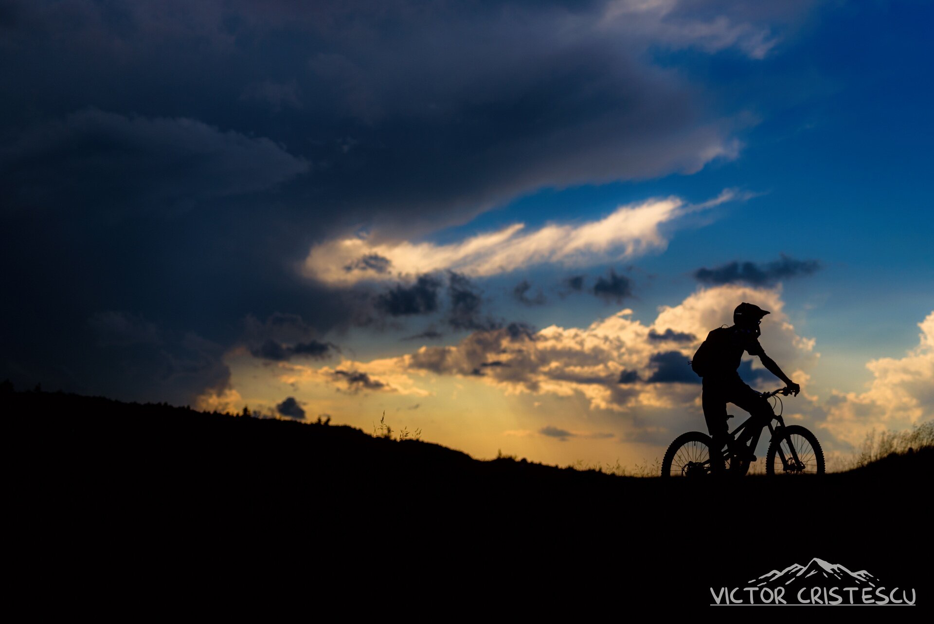 Mountain biker silhouetted against the sunset on a Carpathian ridgeline
