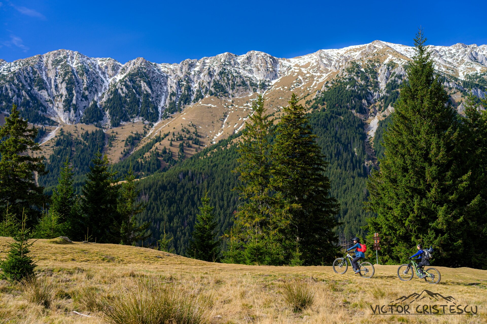 Riders on golden meadows below the snow-dusted Piatra Craiului limestone ridge